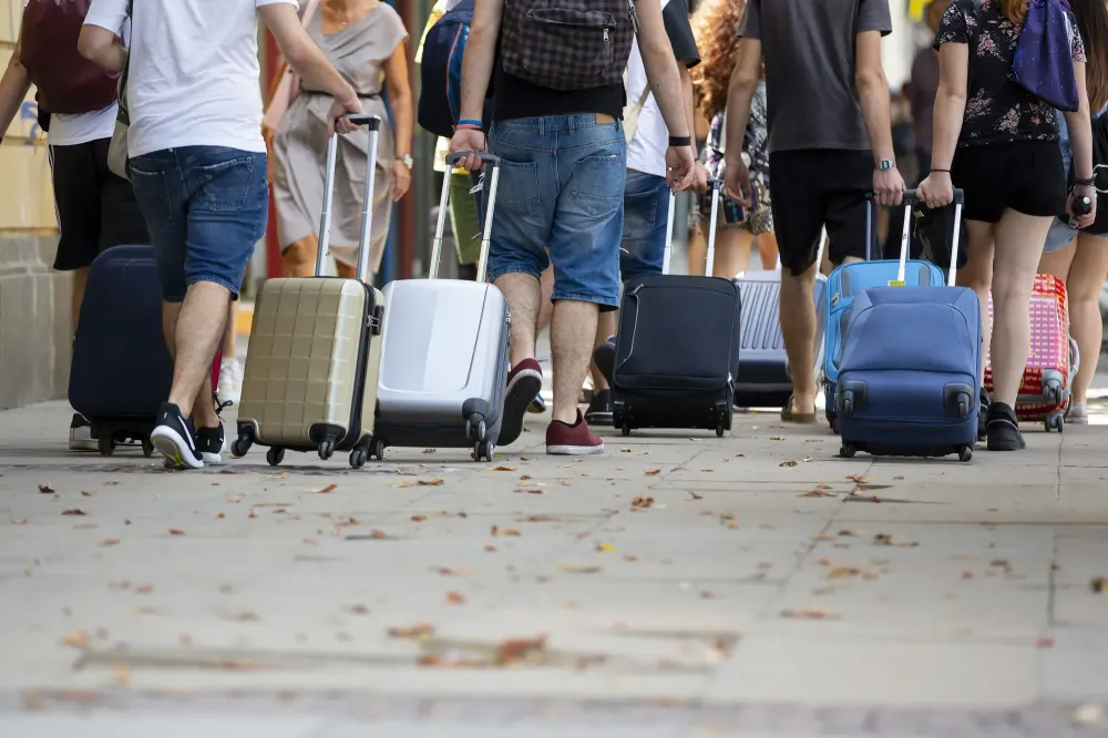 People pulling rolling suitcases in large crowd